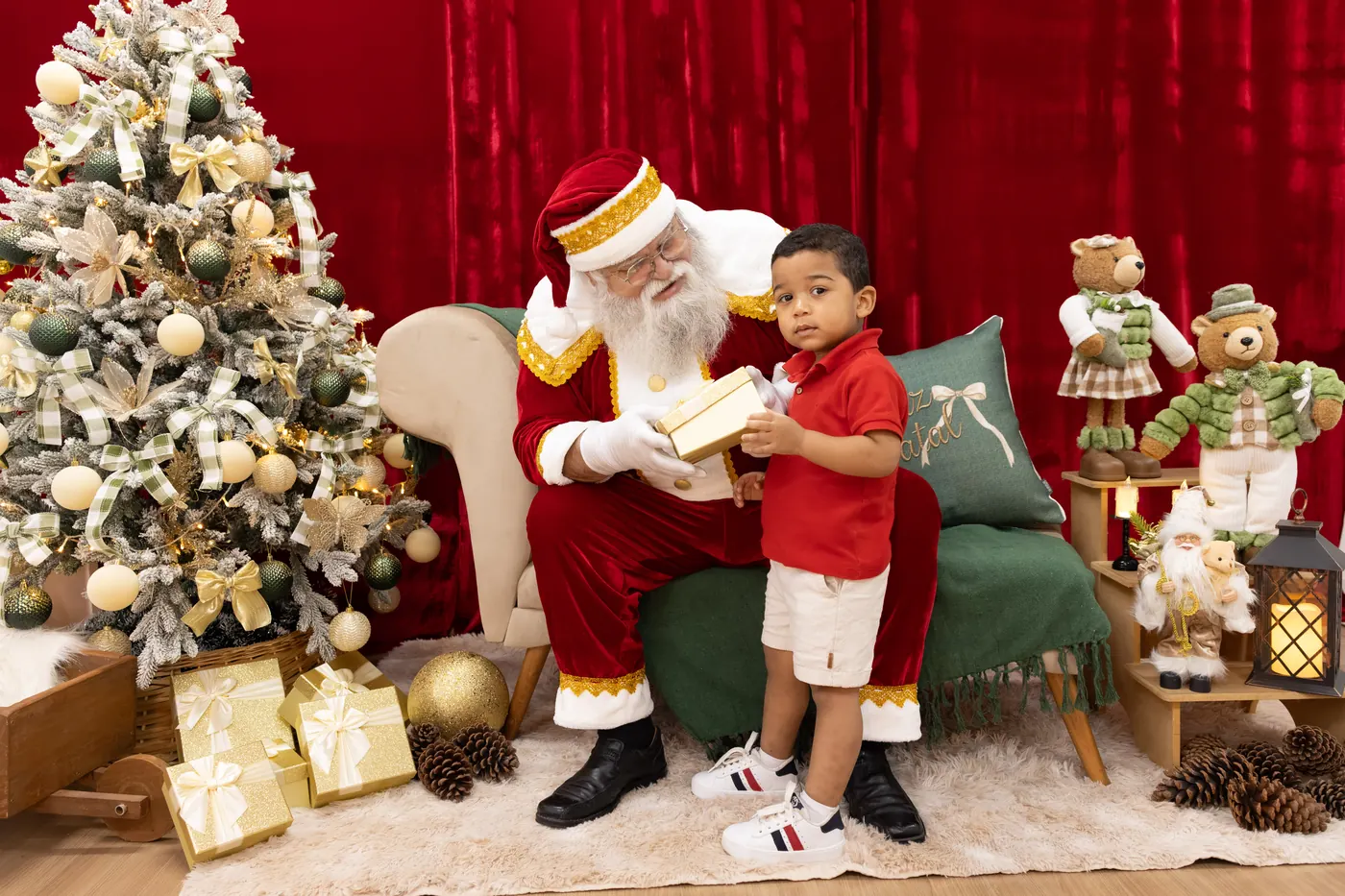 Menino recebendo presente do Papai Noel ao lado da árvore