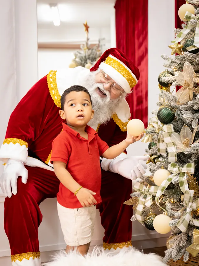 Menino ao lado do Papai Noel olhando para ele, encantado